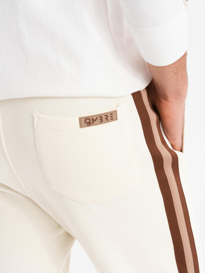 Dresowe męskie spodnie z lampasami i ściągaczami na nogawkach – kremowe V3 OM-PASK-0258