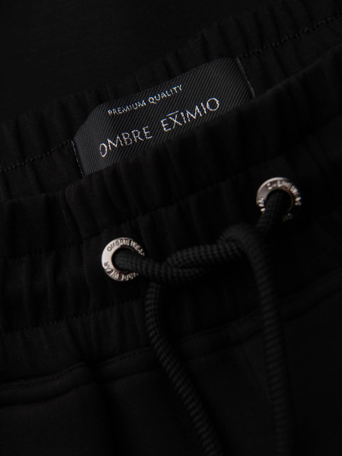 Spodnie dresowe męskie ze ściągaczami w nogawkach i gumowym nadrukiem – czarne V1 OM-PASK-0223